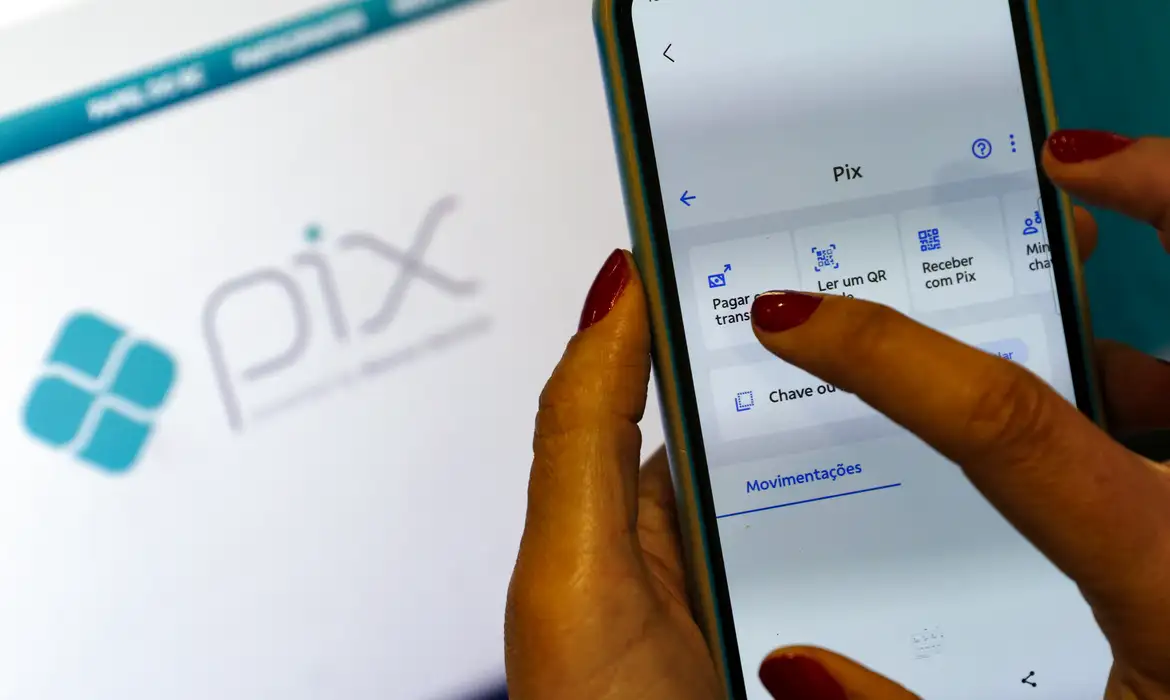 Mão feminina acessando o menu Pix em smartphone com tela exibindo opções de transferência, simbolizando o funcionamento normal do Pix na Copa.