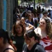 Fila de pessoas caminhando em ambiente urbano durante realização da Prova Nacional Docente.