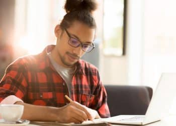 Candidato anota ideias em caderno ao lado do notebook enquanto estuda os temas da redação do Enem 2026