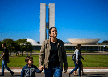 Pai segura a mão do filho pequeno em frente ao prédio do Congresso Nacional