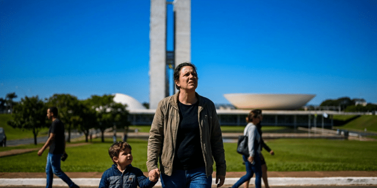 Pai segura a mão do filho pequeno em frente ao prédio do Congresso Nacional