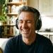Homem ouvindo música com fones, lembrando momentos da adolescência.
