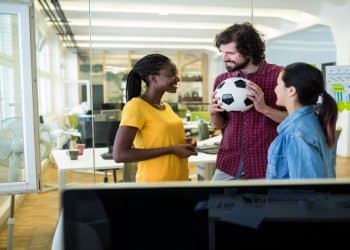 Profissionais no escritório com uma bola de futebol, unindo treino esportivo e qualificação na carreira