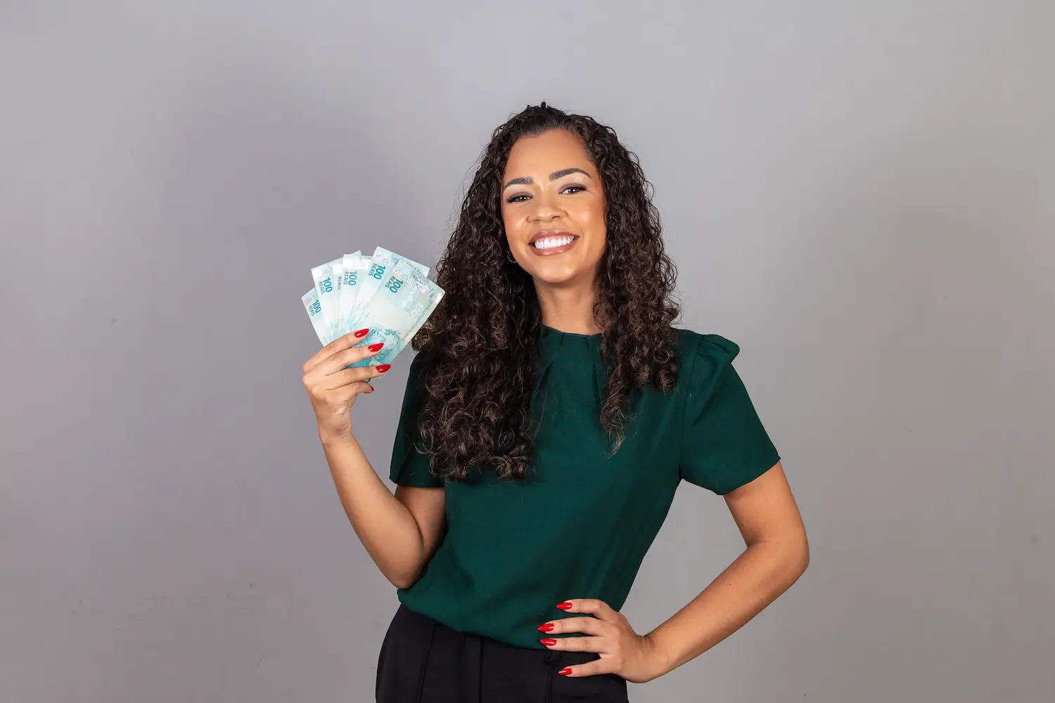 Mulher sorrindo segurando cédulas de dinheiro, representando conversa sobre salário e privacidade financeira.