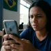 Mulher preocupada olhando para o celular enquanto tenta recuperar o acesso a uma conta online.