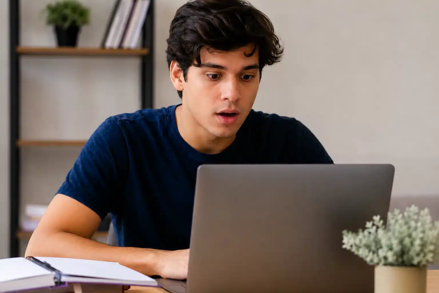 Estudante olhando para o computador com expressão de atenção e surpresa, representando os erros que podem levar à nota zero na redação do Enem.