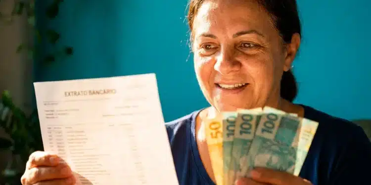 Mulher segura extrato bancário e notas de real após verificar ressarcimento de descontos indevidos do INSS.