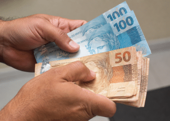 Mãos segurando e contando notas de dinheiro representando saque-aniversário do FGTS.