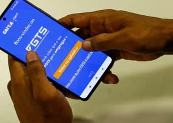 Imagem ilustrativa de uma pessoa segurando o celular com o aplicativo FGTS aberto, usado para fazer o saque-aniversário.