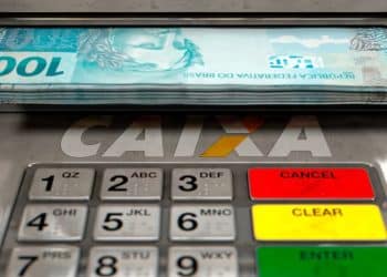 Dinheiro saindo de caixa eletrônico da CAIXA, que paga o Saque Calamidade do FGTS de até R$ 6.220