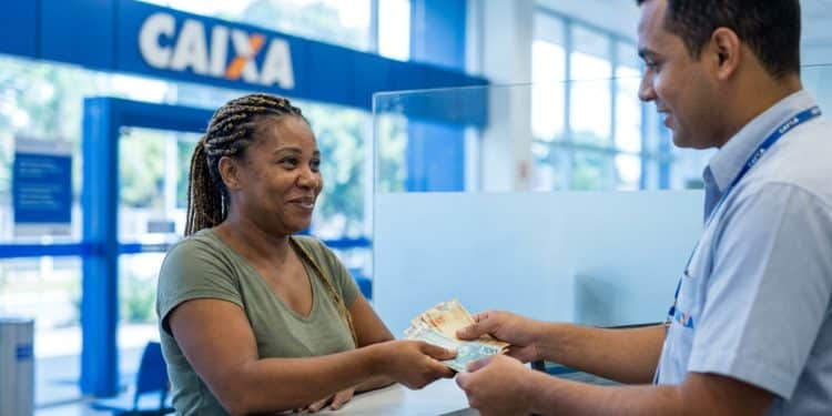 Trabalhadora recebe o Saque Calamidade do FGTS de até R$ 6.220 em uma agência da Caixa.