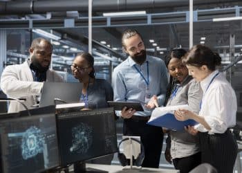 Equipe de profissionais de tecnologia analisa dados em monitores e tablet, representando os setores que pagam bônus acima de 30% do salário-base.