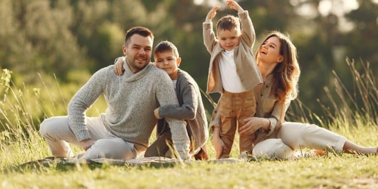Família reunida ao ar livre ilustra a discussão entre ter filhos e felicidade no dia a dia