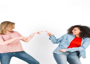 Duas mulheres sorriem e se olham frente a frente, representando o contato visual prolongado durante uma conversa