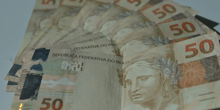 Notas de cinquenta reais espalhadas, representando os valores do abono salarial PIS/Pasep liberados em 2026.