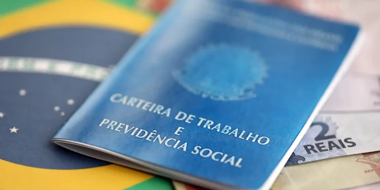 Carteira de trabalho sobre cédulas de real representa o pedido de antecipação do 13º salário durante as férias.