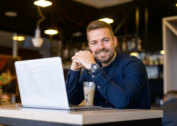 Homem sorrindo em seu ambiente de trabalho.