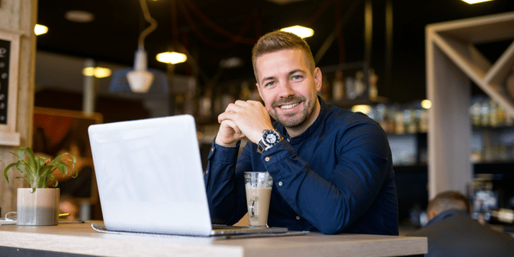 Homem sorrindo em seu ambiente de trabalho.
