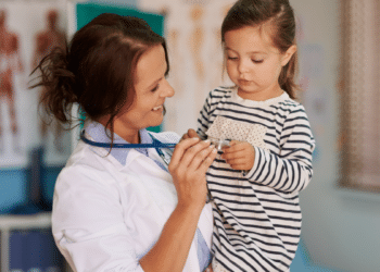 Pediatra sorridente interage com criança em consultório médico.