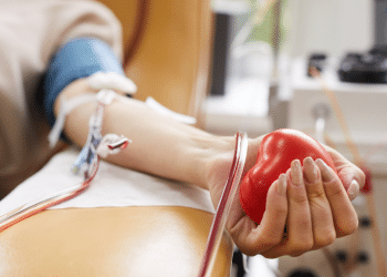 Doação de sangue com foco na coleta e coração de borracha vermelho.