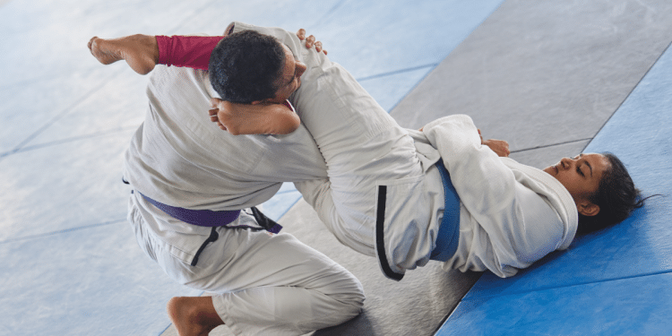 Lutadores executam finalização no tatame durante treino de jiu-jitsu.