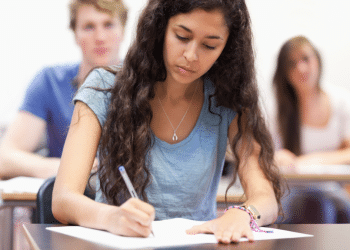 Jovem concentrada realizando prova em sala de aula.