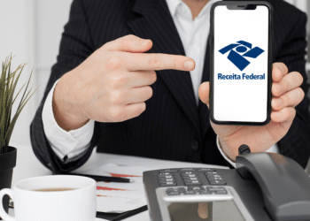 Executivo aponta para aplicativo da Receita Federal em smartphone.