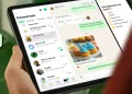 Pessoa segura um iPad com o WhatsApp aberto na tela de conversas e recursos de mensagens.