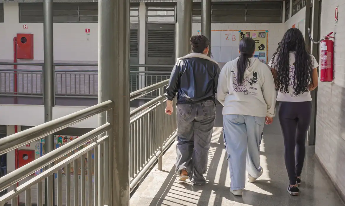 Estudantes caminham pelo corredor de uma escola, referência aos participantes que já podem consultar o resultado dos recursos de atendimento especializado do Enem 2026