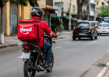 Entregador do iFood em motocicleta circulando pela cidade durante atividade profissional.