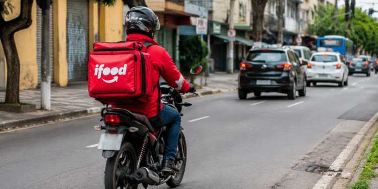 Entregador do iFood em motocicleta circulando pela cidade durante atividade profissional.