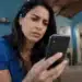 Mulher consulta celular em casa para verificar chamadas suspeitas e evitar ligações de telemarketing