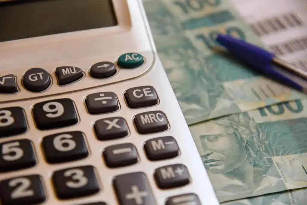 Calculadora ao lado de cédulas de real representa o cálculo do valor do lucro do FGTS a ser recebido pelos trabalhadores em 2026.