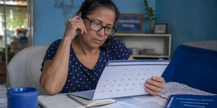 Mulher consultando calendário em casa, representando as datas de pagamento do INSS de julho a dezembro de 2026.