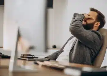 Homem em ambiente de escritório demonstrando cansaço e sobrecarga emocional após rotina intensa de trabalho e responsabilidades.
