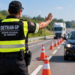 Agente estadual de trânsito do Detran-SP realiza fiscalização em rodovia com cones de sinalização.