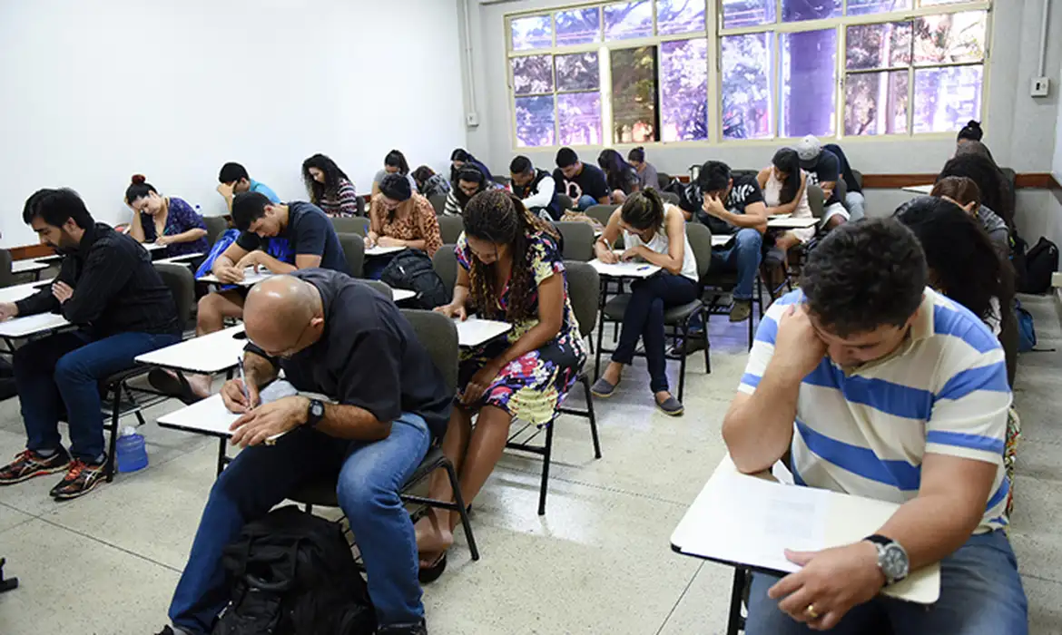 Participantes em carteiras individuais em uma sala de aplicação de prova, em imagem que ilustra o dia do Encceja 2026, marcado para 23 de agosto.