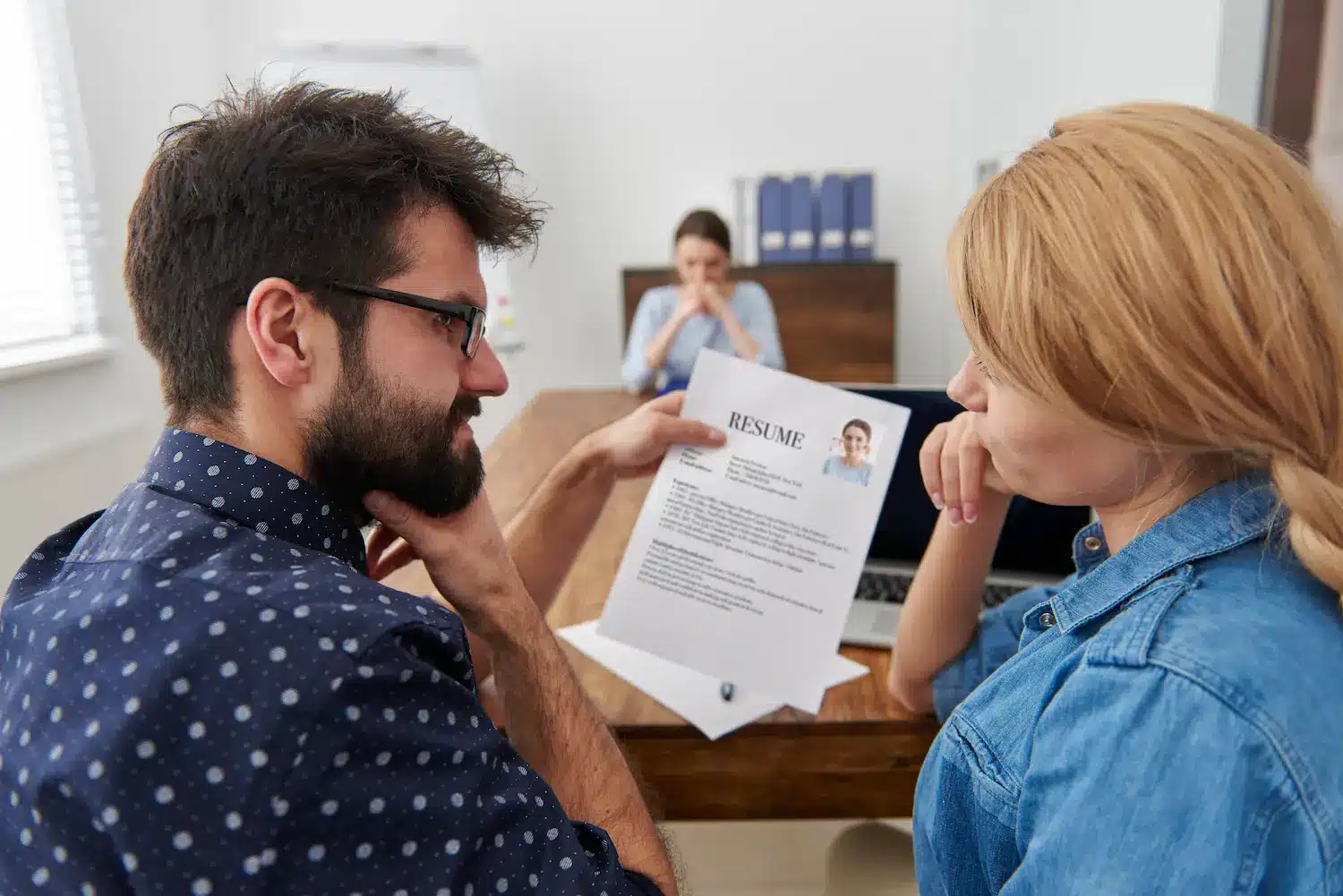 Profissionais analisam currículo com foto durante processo de contratação.
