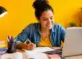 Jovem realiza estudos online com notebook e material didático, representando os cursos profissionalizantes gratuitos.