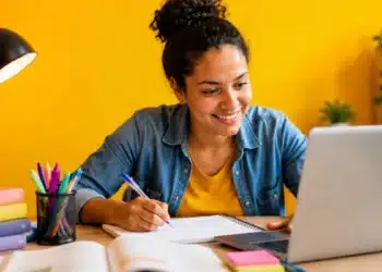 Jovem realiza estudos online com notebook e material didático, representando os cursos profissionalizantes gratuitos.