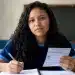 Estudante brasileiro em sala de aula segurando cartão de inscrição e caneta, em preparação para o Enem