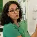 Professora escrevendo “descoberto” no quadro em sala de aula, representando a forma correta entre “descoberto” e “descobrido”.