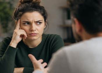 Mulher escuta com expressão contrariada durante uma discussão, situação em que a frase "você me fez sentir" costuma aparecer e transferir ao outro a responsabilidade pelas emoções