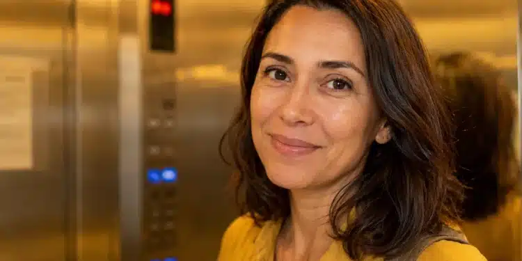 Mulher brasileira sorrindo dentro de um elevador residencial, representando o hábito de dar bom dia.