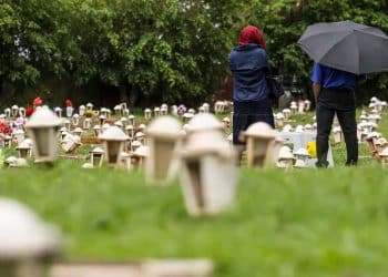 Pessoas caminham por um cemitério em dia nublado, imagem ilustrativa da profissão de agente funerário escolhida por um campeão do mundo após deixar o futebol.