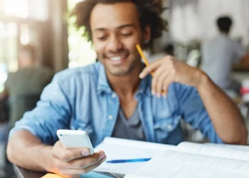 Estudante consulta simulados e exercícios do Enem pelo celular enquanto estuda.