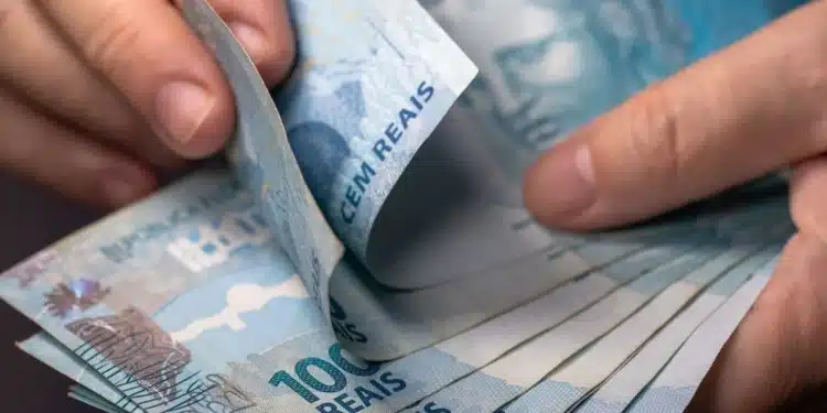Pessoa contando cédulas de real representa o pagamento do lucro do FGTS confirmado pela Caixa em 2026.