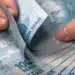 Pessoa contando cédulas de real representa o pagamento do lucro do FGTS confirmado pela Caixa em 2026.