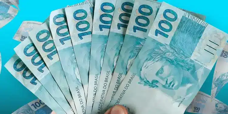 Notas de R$ 100 representando o pagamento, com valor de R$ 1.216 liberado em julho.