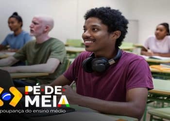 Estudante sorri em sala de aula com colegas ao fundo, ilustrando os alunos da EJA atendidos pelo Pé-de-Meia
